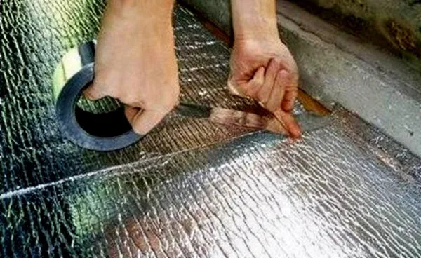 Руки склеивают листы утеплителя строительным скотчем